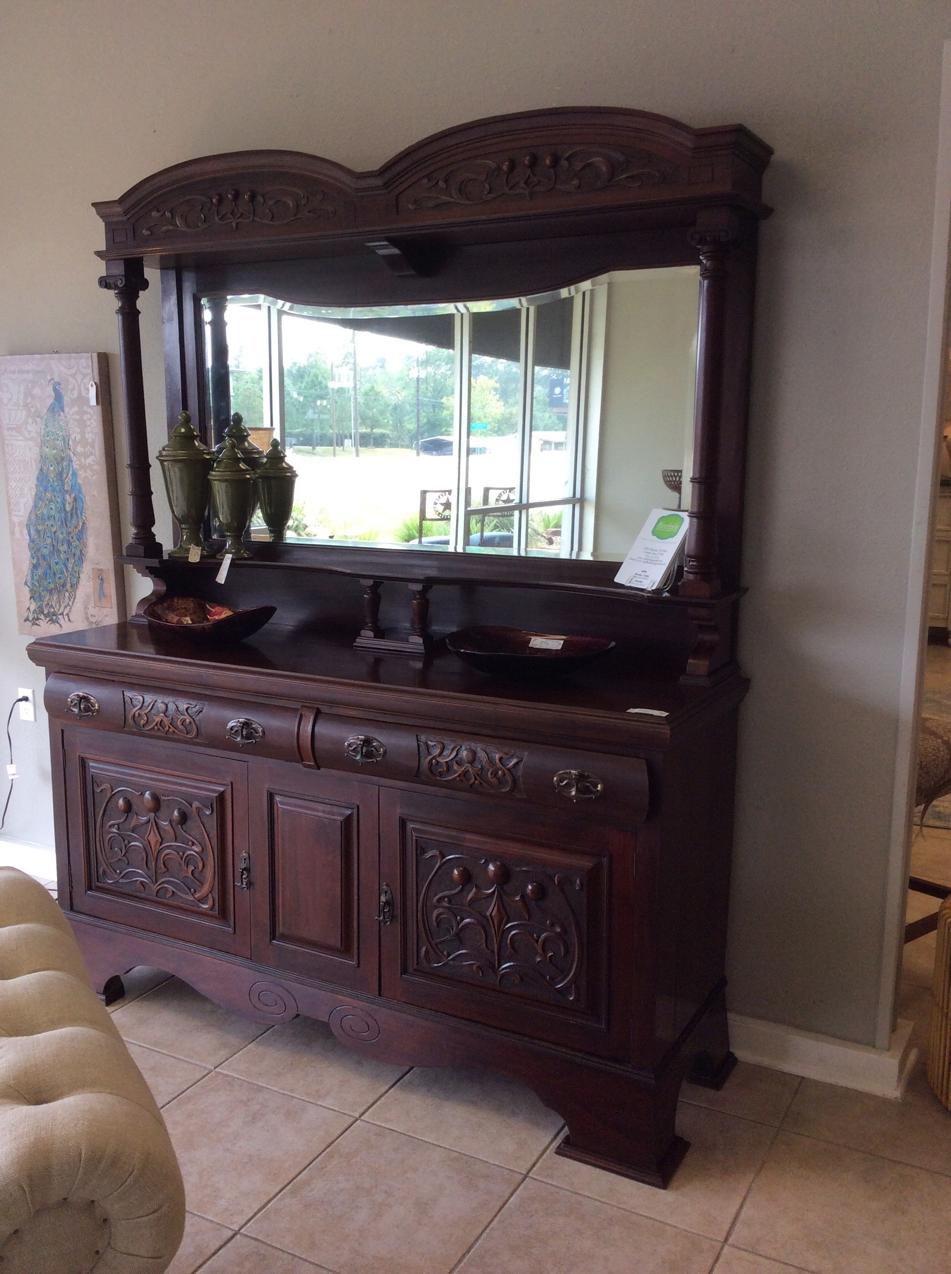 This could be called a statement piece indeed, it's large, bold and dramatic! It features a beauiful dark wood finish, lots of carved details,display/storage space, shelves and a beautiful beveled glass mirror.
