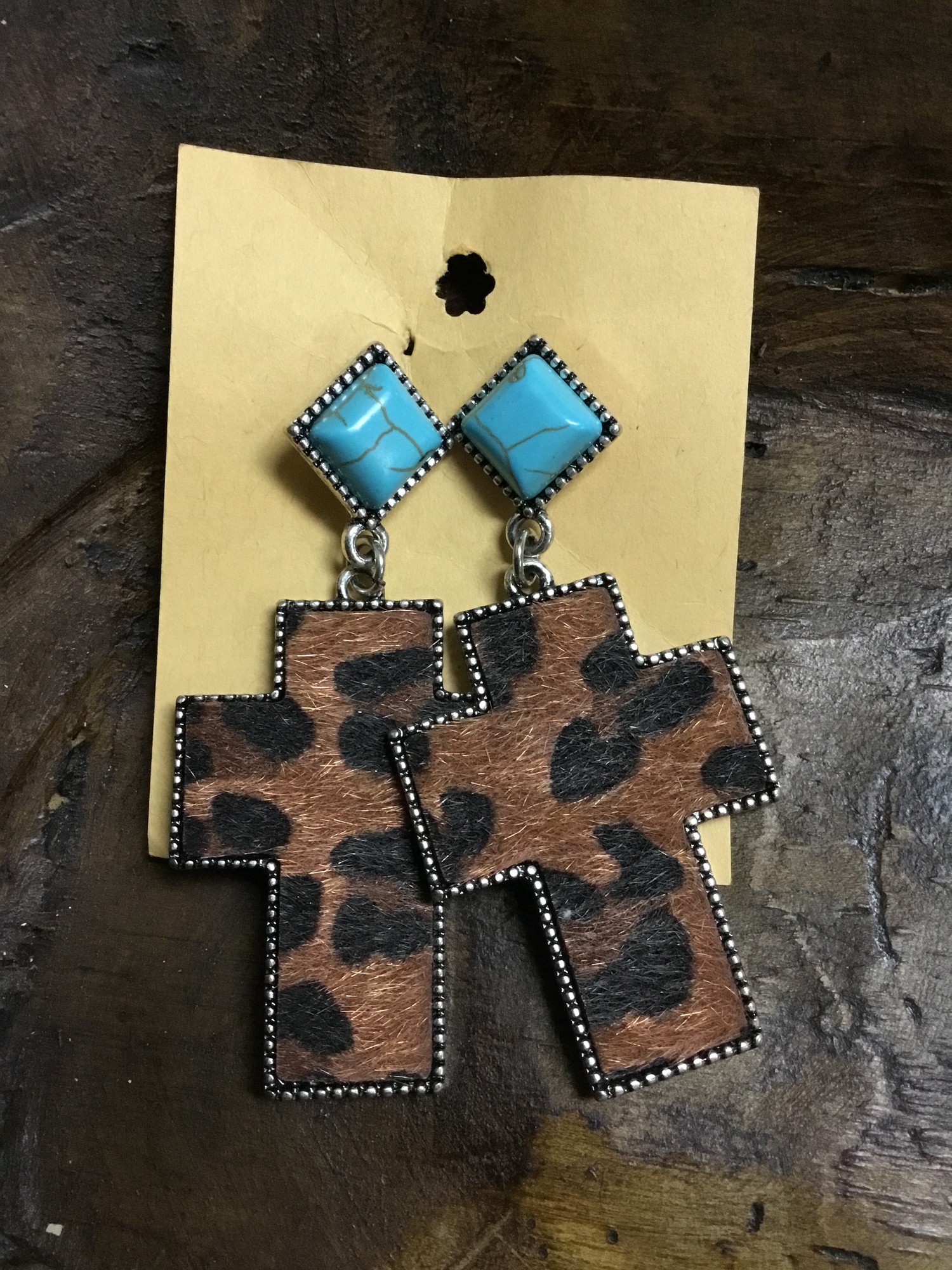 These earrings are in silver tone. The post is diamond turquose shape and the cross is leopard cow hide. They are light weight. 3in long.