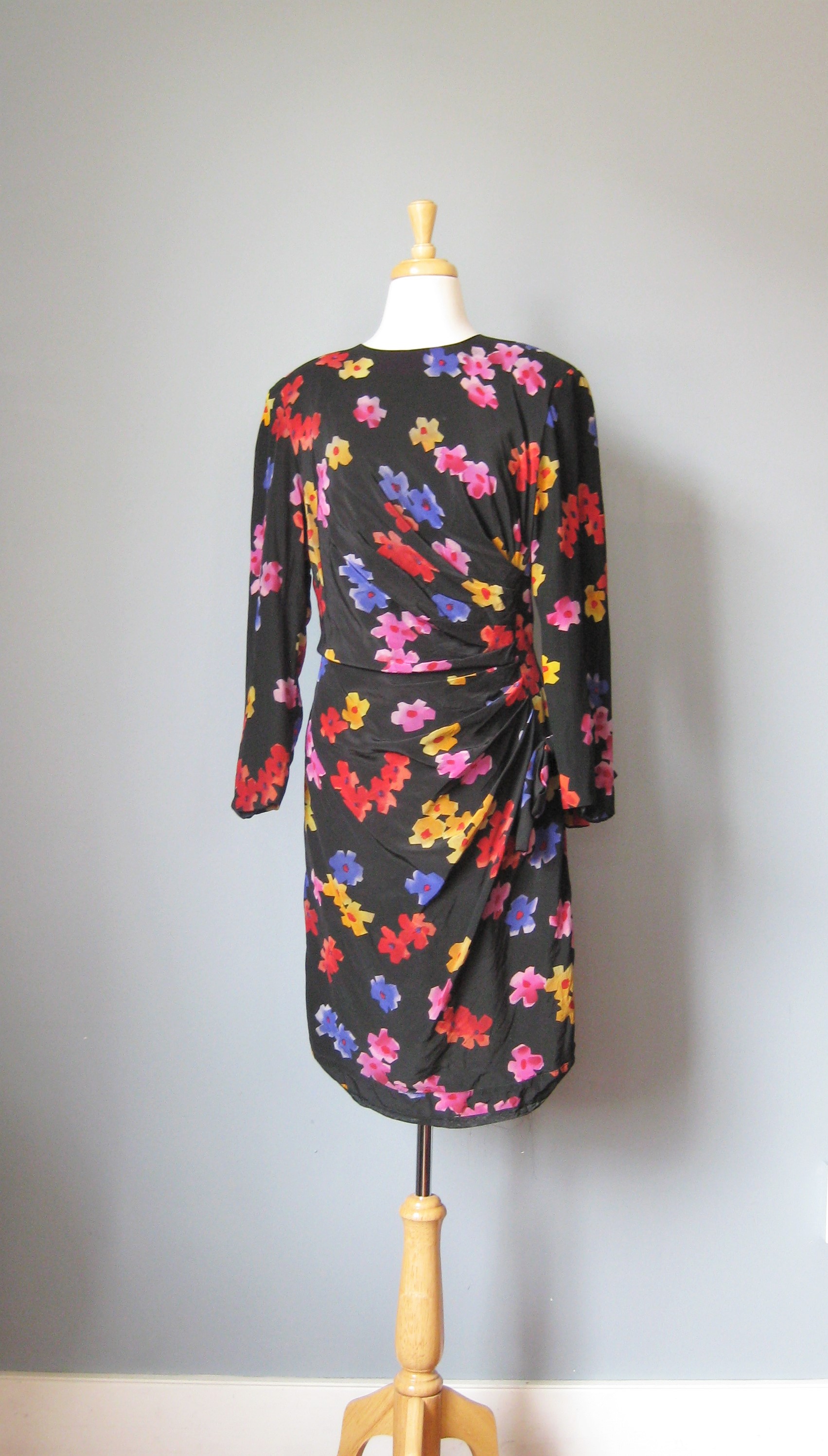 Scaasi floral silk fitted cocktail dress.
Black background with multi color floral pattern
The dress is shaped with ruching to the side for a very flattering silhouette
Fully lined
Jewel neckline
Long sleeves
shoulder pads
Marked size 14, but it would be small for a modern size 14
Flat measurements
Shoulder to shoulder: 17in
Armpit to Armpit: 20in
Waist: 17in
Hips: 20in

Thank you for looking.
#14219