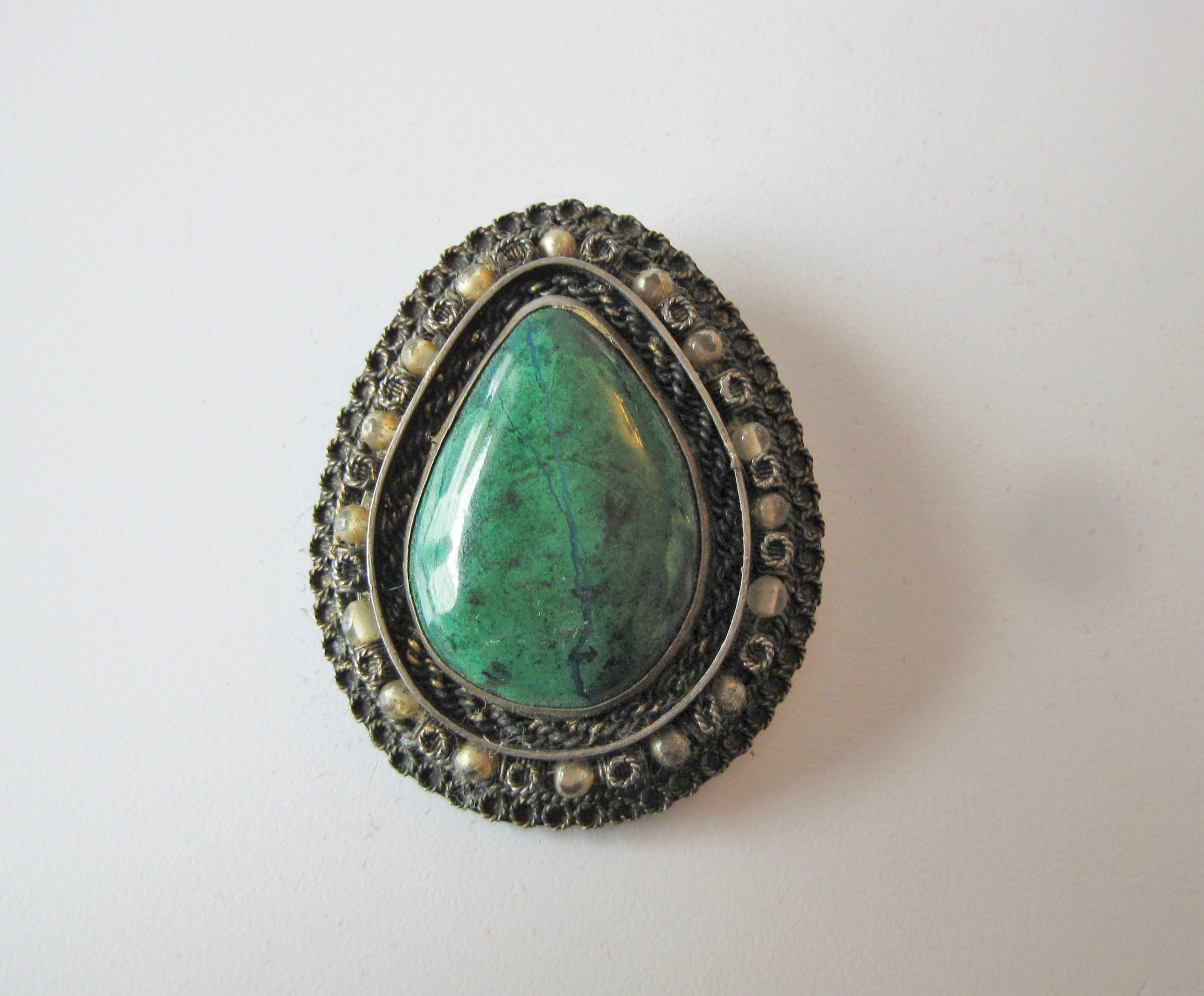 Stunning Old brooch in a silver setting with a polished green stone
It has both a pin and a bale on the back so it can be used as a pendant or a brooch
The stone has a thin almost blue vein running top to bottom
I don't know what the stone is but it could be aventurine , green marble or perhaps malachite
I believe it was made in Israel and is also sterling (based on another almost identical brooch I found online) but there are no markings or hallmarks on the pin so be aware.

The stone is a polished cabochon in perfect condition, the metal setting is in perfect working conditions but showing signs of age as you can see.

1.5 wide x 2in tall

Thanks for looking!
#14826