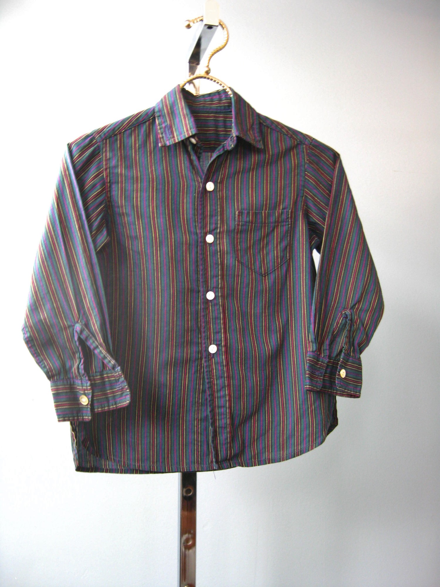 Here's a nice cotton button down shirt for your little gentleman.
Dark Blue cotton with red yellow and white narrow stripes.
Button Cuffs
Little Chest pocket.

Measurements:
Chest : 24in
Length: 17 1/2in
Neck: 11in
Sleeve: 14in

This should fit a toddler size 2T

Thanks for looking!