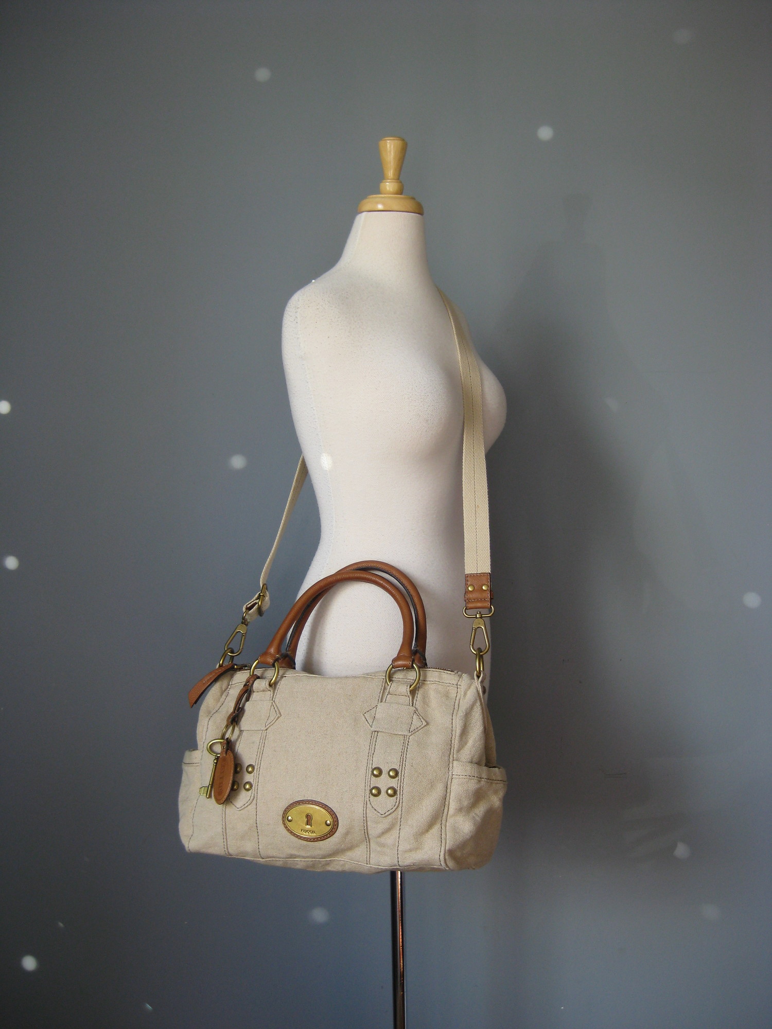 fabulous Fossil satchel in beige canvas with brown leather trim.
Double leather handles and a detachable adjustible web shoulder strap
Antique brass hardware
Key bag charm and leather luggage tag
two exterior slip pockets on the sides
Chevron striped fabric lining

Super clean inside and out
tiny bit of use on the brass hardware medallion

13in x 9in x 5in
Handle drop: 6.25in
Strap drop at max: 24.5in

Thanks for looking!
#18049

Please see my eBay store for other terrific Fossil and other bags