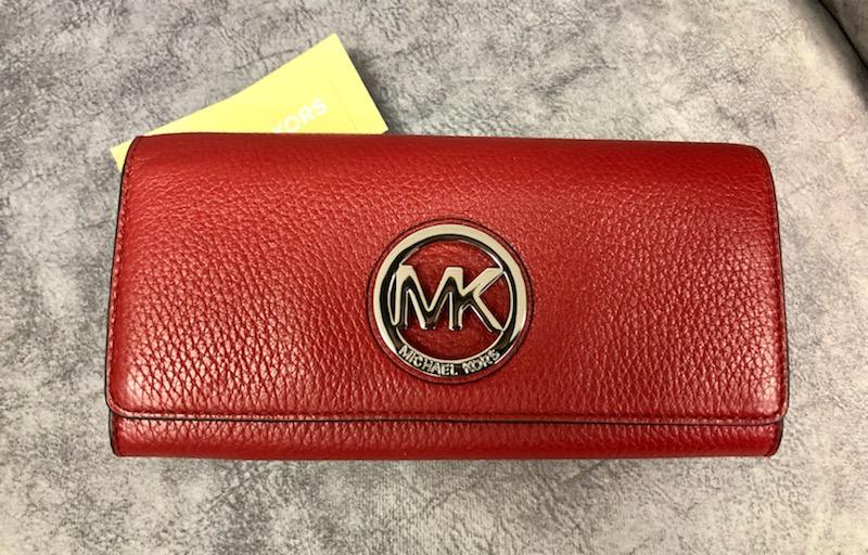 Michael Kors Leather Wallet
FULTON - Red Flap Continental
Original Retail Price:  $178.00
 Gorgeous pebbled leather
* Polished silver tone hardware
* Flap style snap closure
* Open slip pocket on the back
* Interior features zippered coin compartment, 14 card slots, and 4 full length bill compartments
* Measures approximately 7.75\" (L) x 4\" (H) x 1\" (W)
This wallet is Brand New with Tags