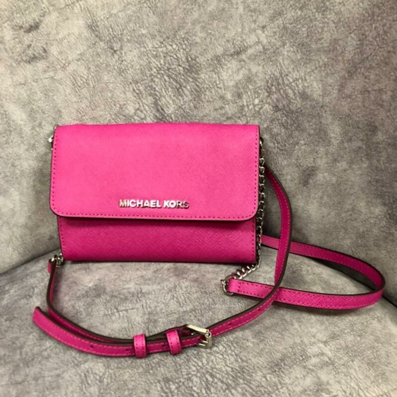Michael Kors
Jet Set Large Phone Watermelon Red Saffiano Leather
Cross Body Bag
Toss this polished wallet in your favorite bag or strap on the adjustable strap for crossbody wear. Smooth leather promises lasting quality with a hint of luxury.
7\"L x 1.5\"W x 5\"H
Like New:  This item may have been worn but has no visible signs of wear.
DESCRIPTION
Saffiano leather
Color is watermelon red (pinkish red)
Adjustable and removable crossbody strap with 23\" drop
Straps are snapped on the inside, removable to be a standalone wallet
Magnetic snap closure
Logo lettering at front
Chic Silver hardware
Slit pocket in back
Interior features three compartments
1 cell phone pocket (you can put the phone here or in the slot pocket in the back)
5 card slots
One zippered pocket for extra security to prevent fallout
7\" W x 5\" H x 1-1/2\" D
Original Retail Price:  $169.00