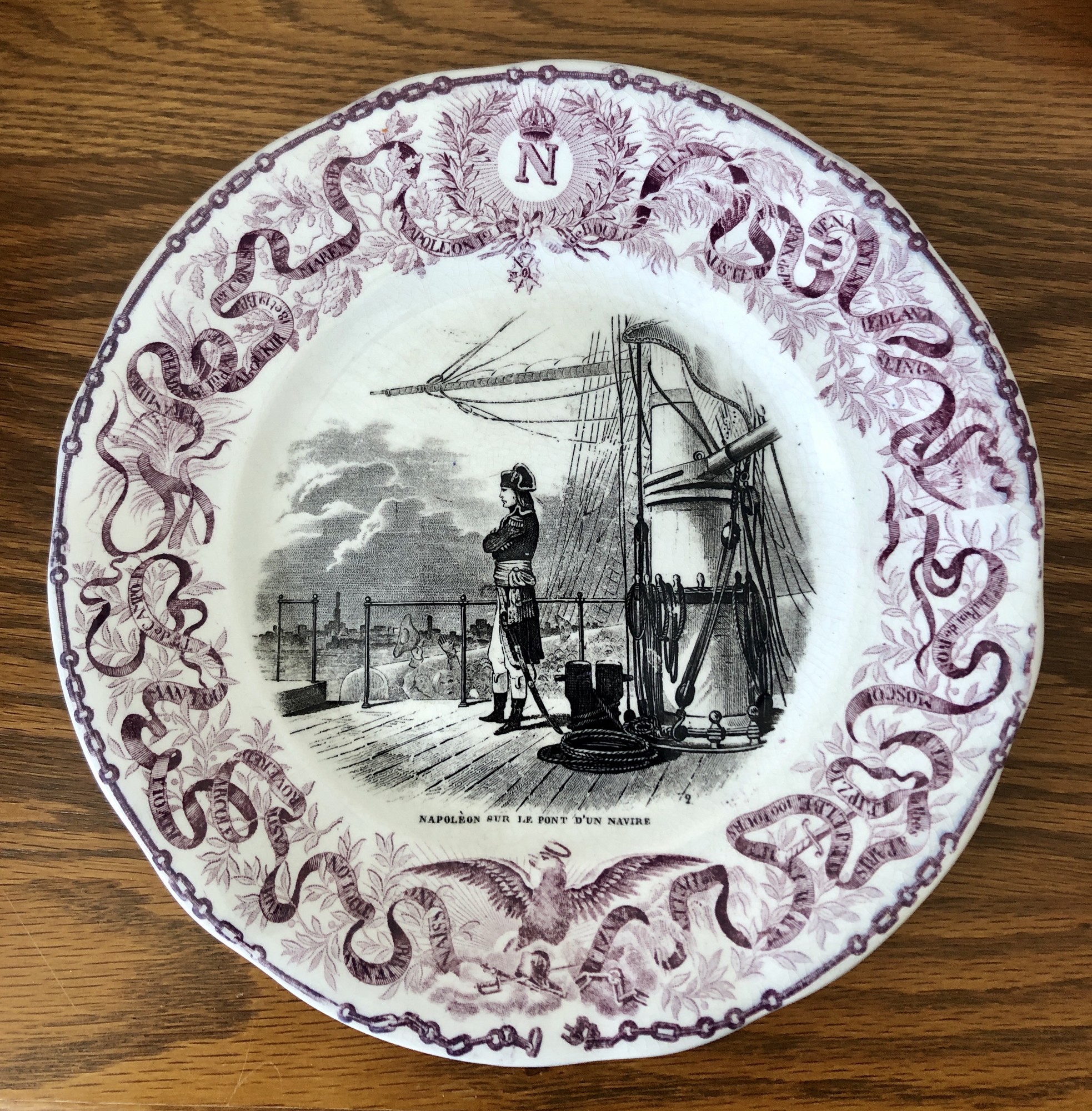 French Napoleon Commerative Assiettes Parlantes Plate. c.1840s Napoleon Sur Le Pont D'un Navire
Assiettes Parlantes, or talking plates, are French transferware plates with sayings on them. The most collectible illustrate the life of a French hero such as the plates depicting Napoleon. Really unusual to find in purple. 8.