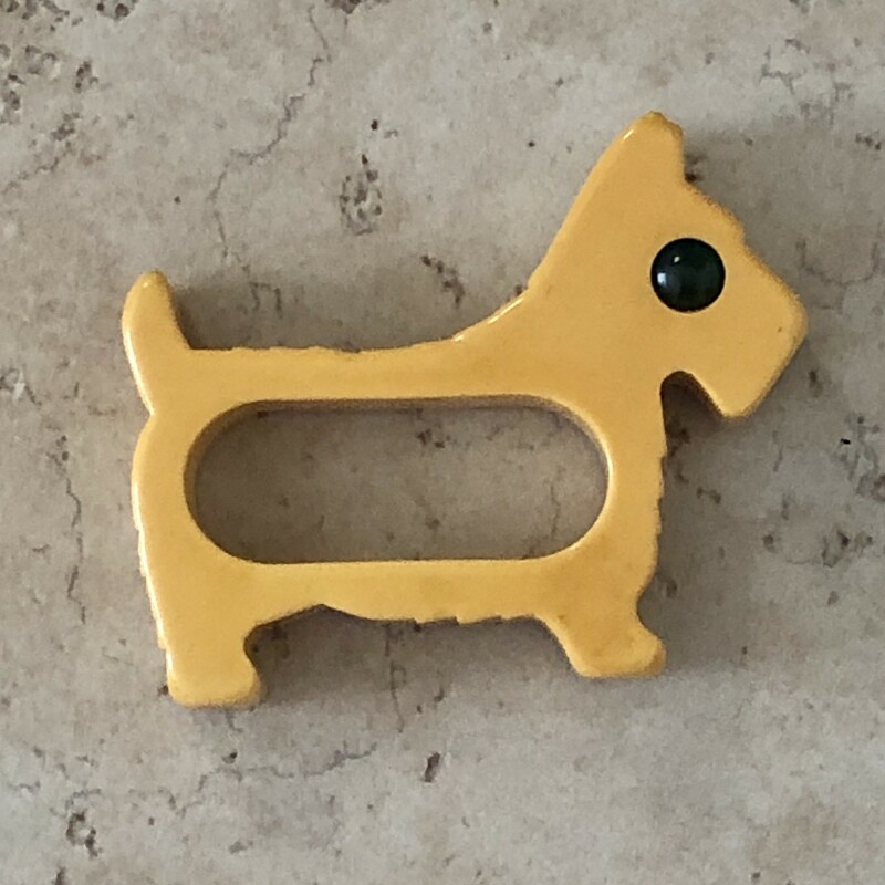 This is a hard to find Bakelite Dog Napkin Ring, He's yellow with green eyes. Size: 2.75in, c.1940s.