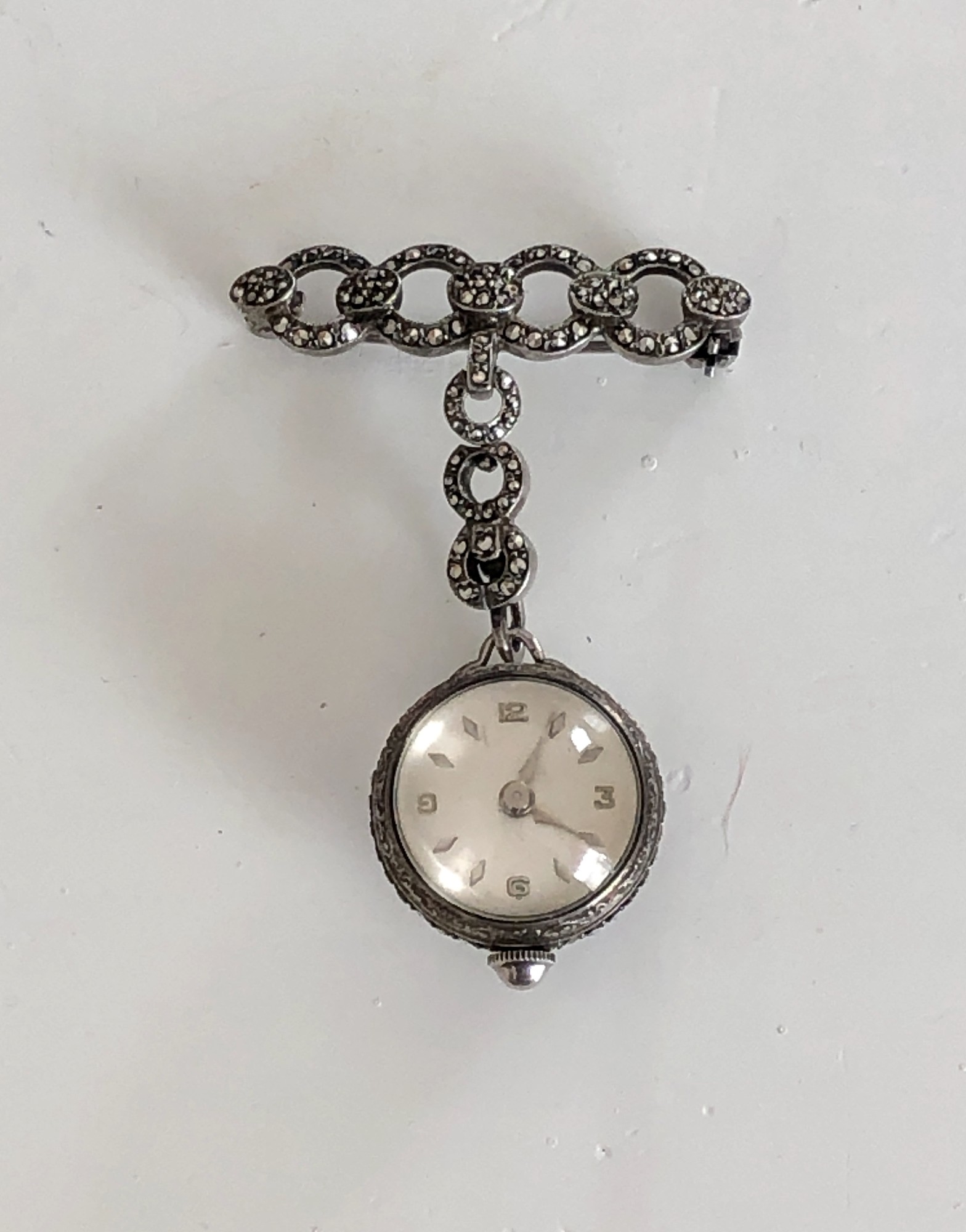 This amazing  watch has a beautiful brooch with secure pin closure and suspends an articulated swinging marcasite encrusted section to hold the ball watch. The watch itself is encircled with bands of shining marcasite. The cream dial has silver markers for the minutes and is marked for Bucherer, 17 Jewel, 800 silver.

The condition of this piece is excellent  and the watch is currently working. This is a timeless and elegant timepiece.