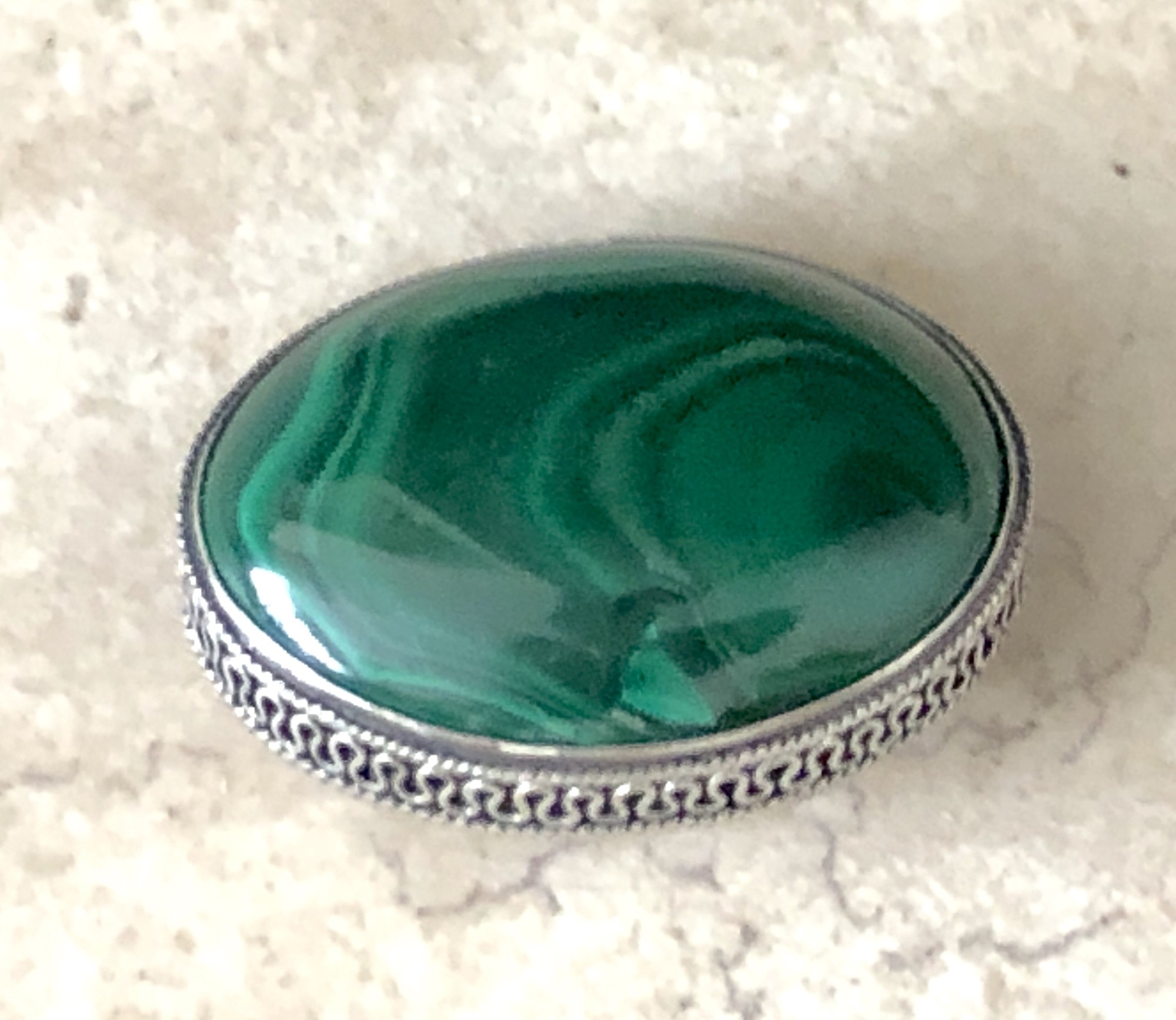 The malachite in this vintage brooch is a rich green confection of waving lines, a beautiful oval of hunter and kelly hued stripes. The ribbon of silver encircling the stone completes this wonderful Mid-Century era  brooch.
Size: 1.25in X 1in