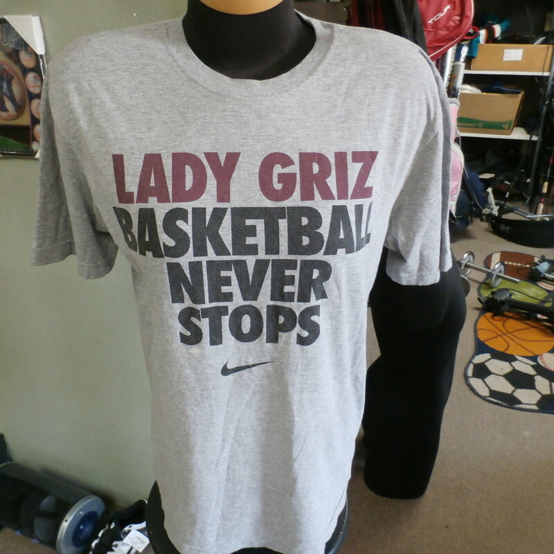 Montana Lady Griz \"Basketball Never Stops\" Nike shirt gray size M #23919
Rating: (see below) 2- Great Condition
Team: Montana Lady Griz
Player: Team
Brand: Nike
Size: Women's Medium-  (Measured: 21\" Wide, length 27\")
Measured: Armpit to armpit; shoulder to hem
Color: Gray
Style: short sleeve; screen printed
Material: 80% cotton 20% polyester
Condition: 2- Great Condition; wrinkled; some pilling and fuzz; material is stretched and worn from wearing and washing; some discoloration and fading; no rips or tears; no stains; the back of the shirt has been signed but the signatures have mostly faded (see photos)
Item #: 23919
Shipping: FREE