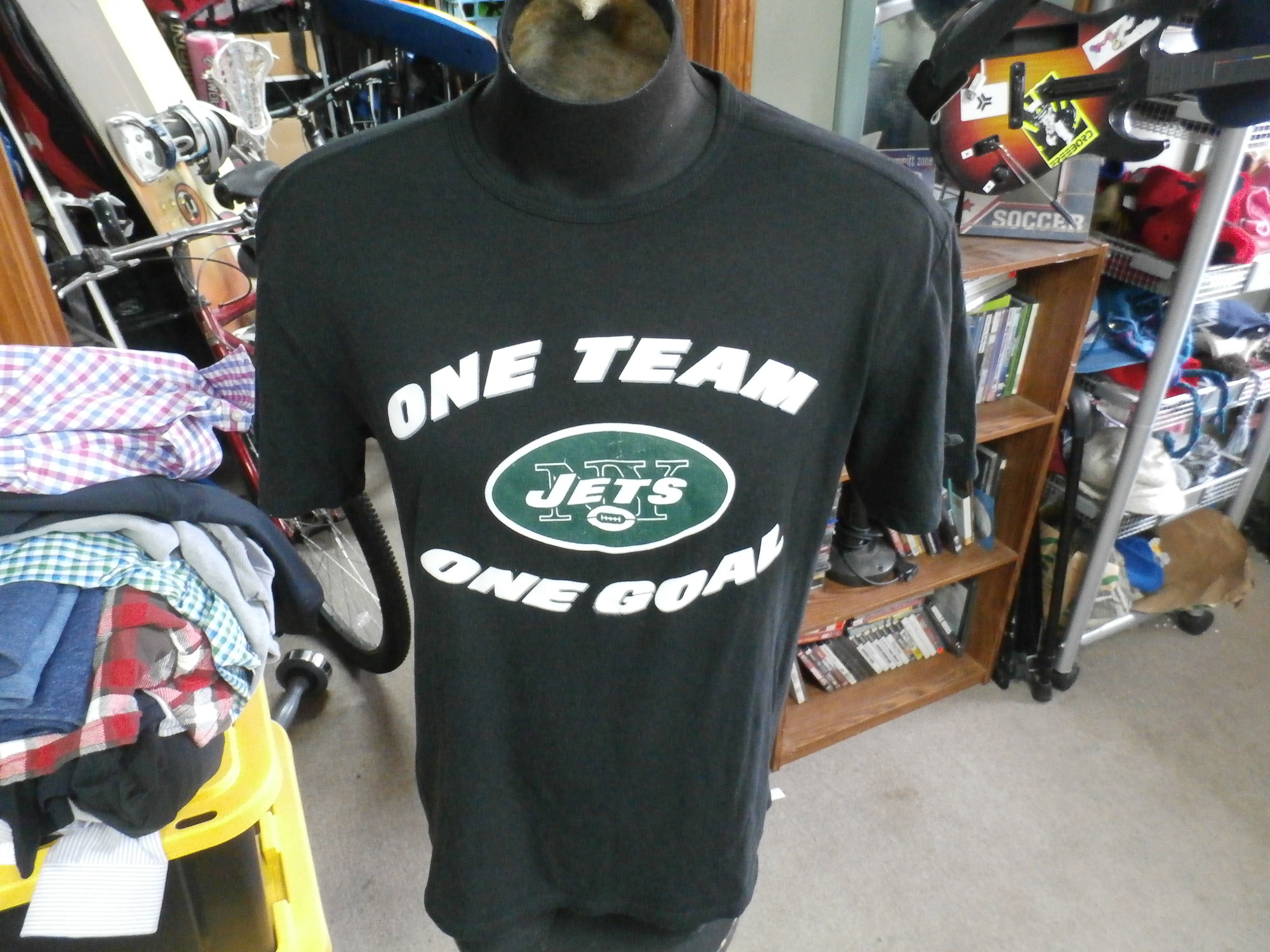 New York Jets \"One Team\" New Era shirt black size tag missing polyblend #29282
Rating: (see below) 3- Good Condition
Team: New York Jets
Player: n/a
Brand: New Era
Size: Tag missing- (Measured Flat: Across chest 21\"; Length 28\")
Measured Flat: underarm to underarm; top of shoulder to bottom hem
Color: black
Style: short sleeve; screen printed
Material: 50% polyester 38% cotton 12% rayon
Condition: 3- Good Condition: minor wear and fuzz from use; printing defect on \"G\" on front (see photos)
Item #: 29282
Shipping: FREE