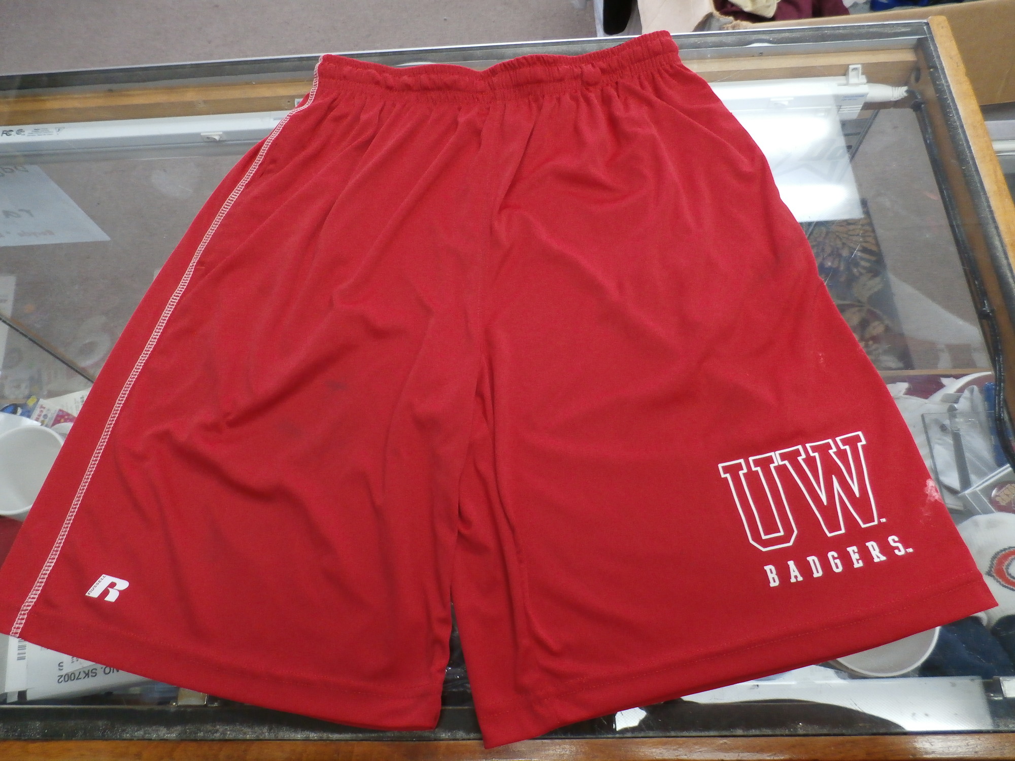 Russell Men's Wisconsin Badgers shorts red size Small polyester #33419
Rating: (see below) 4- Fair Condition
Team: Wisconsin Badgers
Player: Team
Brand: Russell
Size: Men's    Small-  (Measured Flat: Waist 13\"; Length 21\"; Inseam 9\")
Measured flat: hip to hip; hip to hem; and groin to hem
Color: Red
Style: elastic waistband; screen pressed; shorts
Material: 100% polyester
Condition: 4- Fair Condition: wrinkled; minor pilling and fuzz; some stretching from use; there is both white and dark staining in multiple spots on shorts;
Item #: 33419
Shipping: FREE