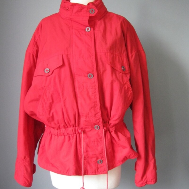 Cinchable red ski shell or jacket  from the 1990s<br />
Brand: At Ease<br />
Zippered front with metal buttons<br />
Hood hides in the zipper around the neck<br />
Blue Quilted satin lining<br />
Bright Red<br />
Size Large<br />
Made in Malaysia<br />
<br />
Flat measurements (Please double where appropriate):<br />
Armpit to armpit: 29in<br />
Length: 25 3/4in<br />
<br />
Thanks for looking!<br />
#25514