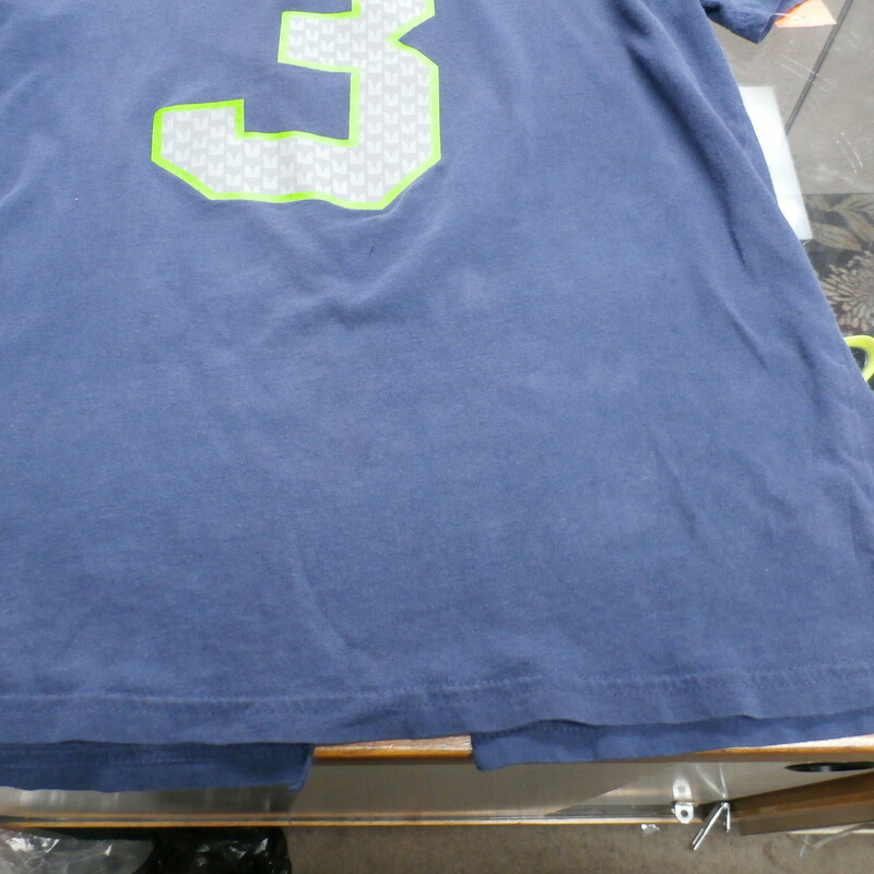Seattle Seahawks YOUTH Russell Wilson Shirt blue size L(14/16) #14735
Rating: (see below) 4 - Fair Condition
Team: Seattle Seahawks
Player: Russell Wilson #3
Brand: NFL
Size:  Large 14-16 YOUTH - (Measured Flat: chest 18\", length 24\")
Measured laying flat: armpit to armpit; top of shoulder to bottom hem
Color: Blue
Style: short sleeve shirt; screen pressed logo;
Material: 100% cotton
Condition: 4 - Fair Condition: wrinkles; missing a piece of fabric along bottom rim; lots of staining; tiny hole on the front; worn out; dirtiness throughout front and back; faded and discolored;
Item #: 14735
Shipping: FREE