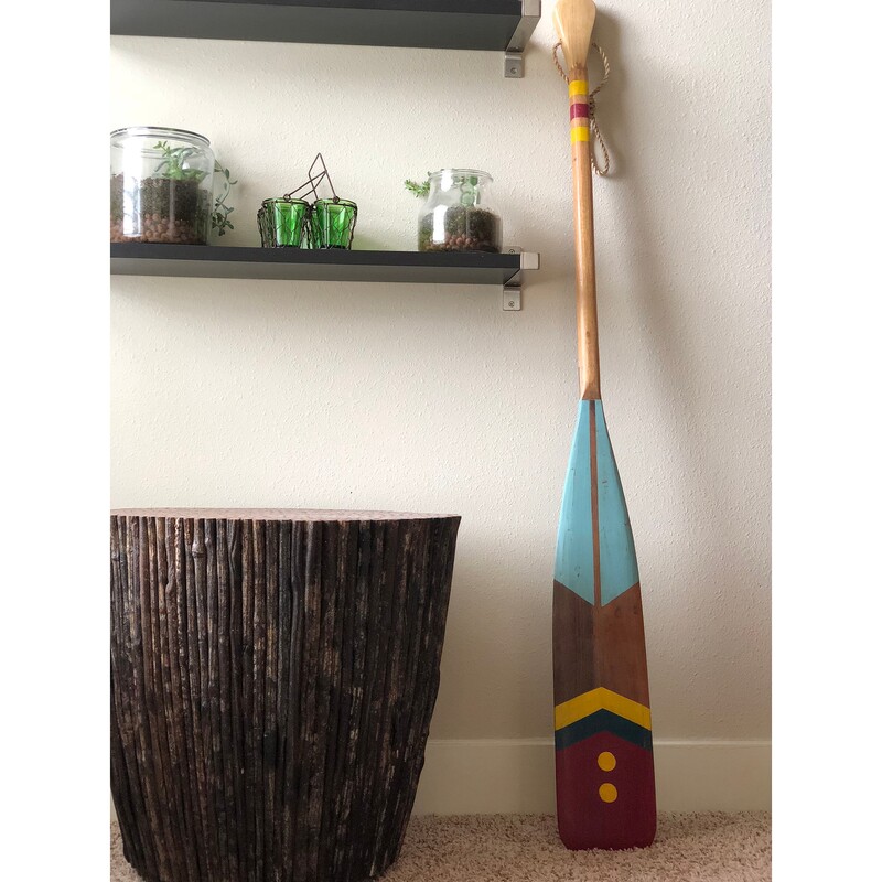 Aqua And Red Oar, 60  L<br />
<br />
This oar is a trophy to summer times on the water. The shape and size is functional, and the color pattern is bold, bringing out a sense of festive summertime nights. The simple, gold buttons on a tidy red back drop give this vintage inspired oar a formal feel.