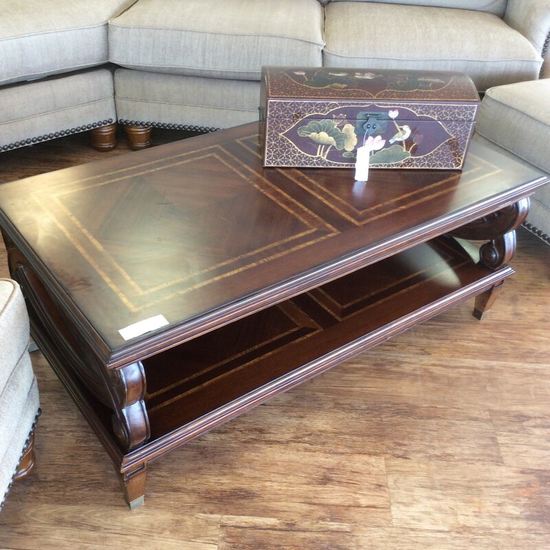 LOVE this compact little coffee table!
It has a inlaid top and a large shelf on the bottom (my cat uses mine to nap in) It is a very pretty two toned brown. The sides have  very pretty carved insets....