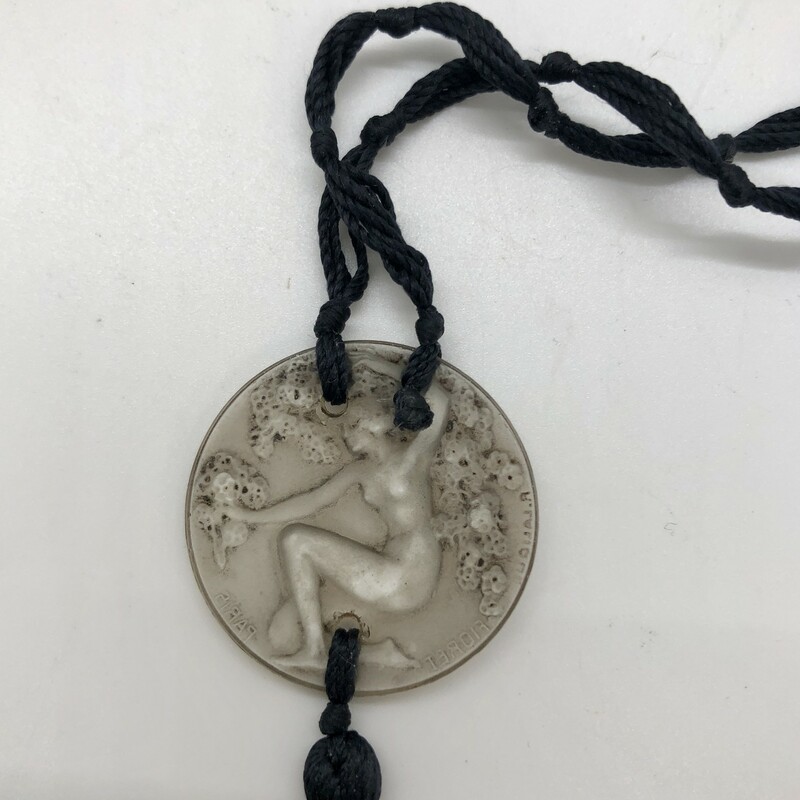 Fabulous and rare Rene Lalique Chose Promise Pendant.<br />
<br />
This pendant was made by Rene Lalique as a decorative hangtag displayed outside the box for Fioret Chose Paris perfume (bottle by Baccarat). Although originally a medallion, they are used as pendants today. The knotted silk cords are original c.1924.<br />
<br />
This is the only authentic hangtag made by Lalique for Fioret. It is clearly signed in the mold Fioret Paris and R. Lalique as seen in the photos. In excellent condition with virtually no nips or flea bites.