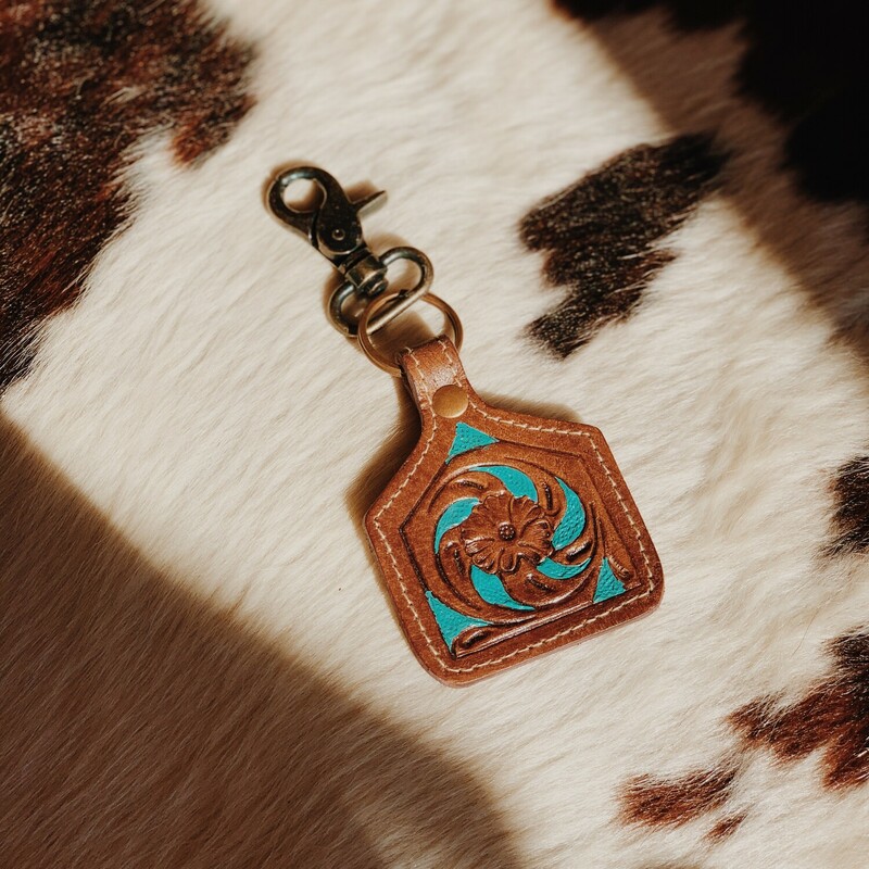 These adorable Myra brand keychains measure 6.5 inches long by 3 inches wide. They feature a beautiful carving detail and turquoise paintings!