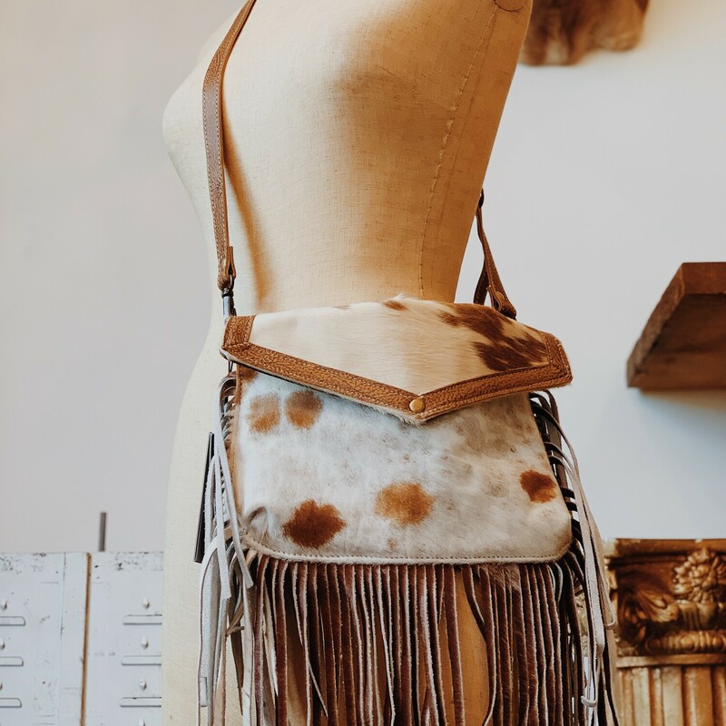 This stylish cowhide, fringe bag adds flare to any outfit! It measures 8 inches by 11 inches and has two extra pockets. Available in two different colors!