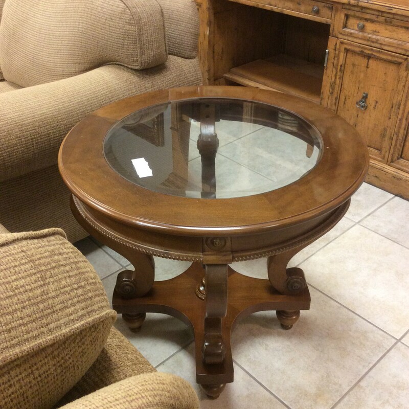 This very pretty round end table has a beveled glass. It is light wood and has swirled curved legs on a base.
Measures 29x26
