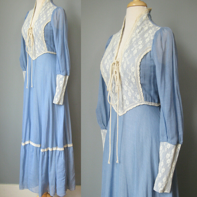 Vintage 1970s Gunne Sax Gown in blue cotton with white/offwhite lace trim.<br />
corset lace front<br />
Low neckline and sweeps up to cover the back of the neck<br />
Gathered skirt is quite full<br />
Juliet type sleeves, blue cotton from the shoulder to the forearm and then tight lace from there to the wrist.  The sleeves have zippers so you can get that tight look but still get in and out of the dress easily.<br />
It's fully lined in white/offwhite soft acetate<br />
<br />
<br />
Almost like new condition.  I found one small hole in the lining as shown and the corset lacing has a brown area also shown.<br />
<br />
Here are the flat measurements please double where appropriate<br />
Shoulder to shoulder: 13<br />
Amrpit to Armpit: 17<br />
Waist: 13<br />
Hips: 20<br />
Length: 57<br />
<br />
Thank you for looking.<br />
#43206