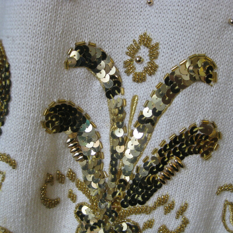 Gorgeous vintage Christmas sweater in slightly unexpected off white and gold.<br />
Lavishly decorated with shiny gold sequins at the bottom edge.<br />
Shoulder pads<br />
55% Ramie and 45% cotton<br />
Marked size Large<br />
<br />
Flat Measurements<br />
Armpit to Armpit: 21<br />
Shoulder to shoulder: 21<br />
Underarm sleeve seam length: 19.5<br />
Width at hem : 20<br />
Length from back neck to hem: 30<br />
<br />
good vintage condition with a very slight shadow at the neckline on the left.<br />
thanks for looking!<br />
<br />
#43171
