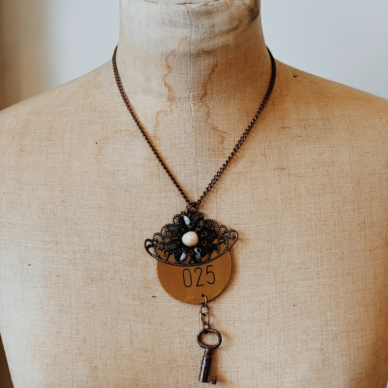 This beautiful, handmade necklace features a brass pendant with a faux pearl and the number 025. It is on a 17 inch chain.