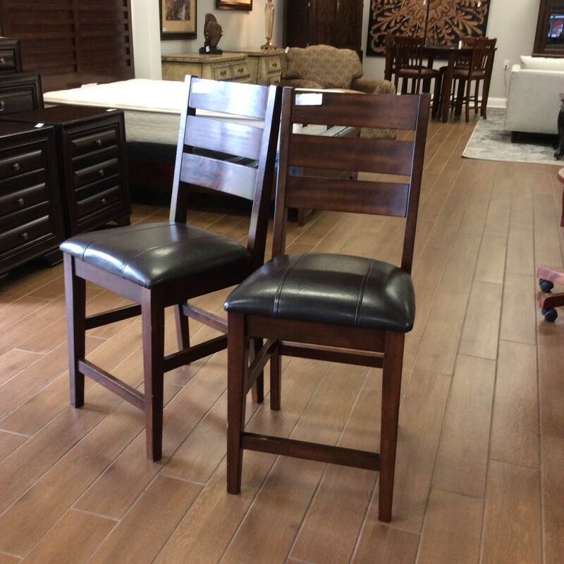 This pair of barstools feature a dark wood finish with distressing . The seats are upholstered in a dark brown vinyl.