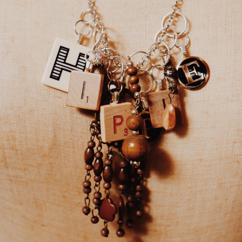 - Hand crafted necklace with hippie spelled out in game pieces<br />
- Silver 25 inch chain<br />
- Assortment of charms and wooden beads
