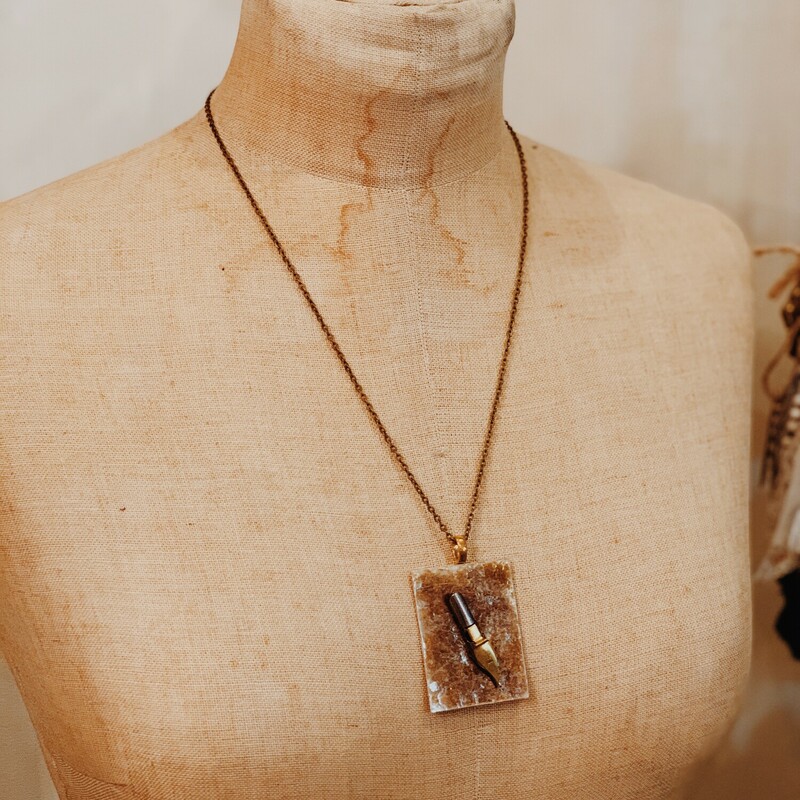 This one of a kind, handmade necklace has an antique calligraphy pen on a brown back drop. It is on a 22 inch chain.