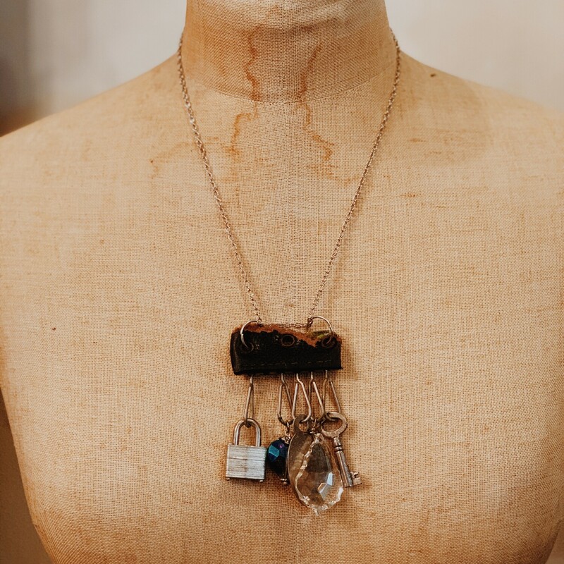 This one of a kind, handmade necklace is perfect for those who love unique! Hanging from leather is a padlock, a key, a crystal, a heart charm, and a silver tag. It is on a 20 inch chain.