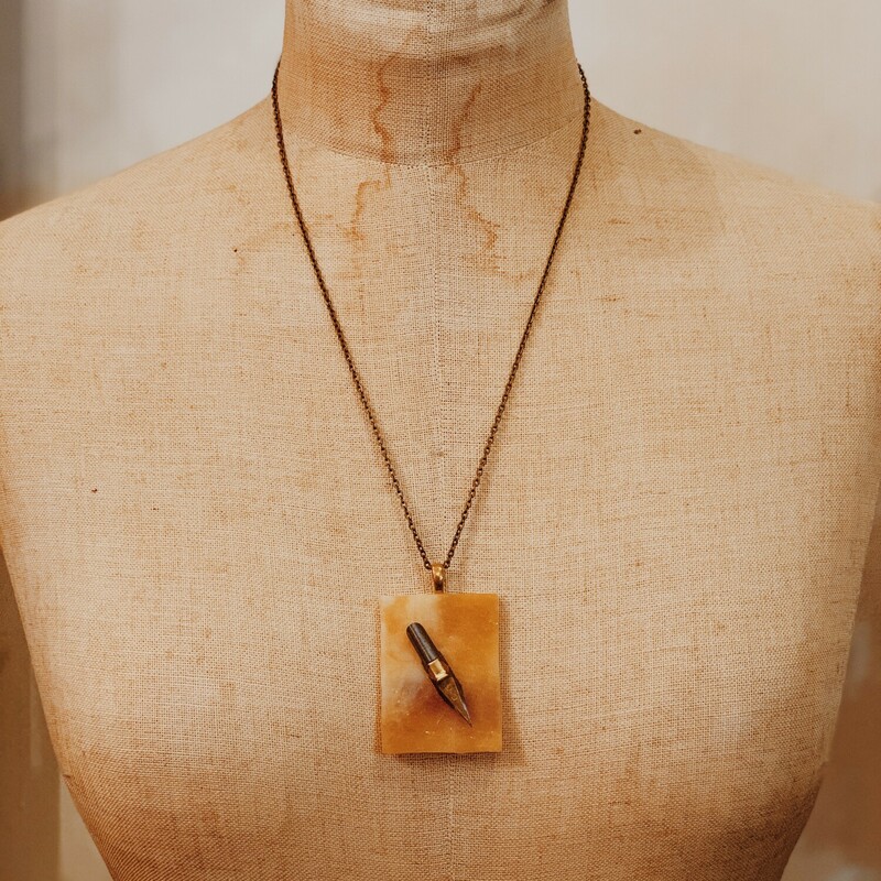 This one of a kind, handmade necklace has an antique calligraphy pen on an orange back drop. It is on a 22 inch chain.