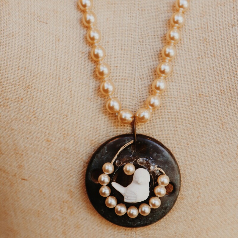 This beautiful, hand crafted necklace is on a 31inch strand of faux pearls. The pendant is a vintage door piece with an adorable bird attatched.