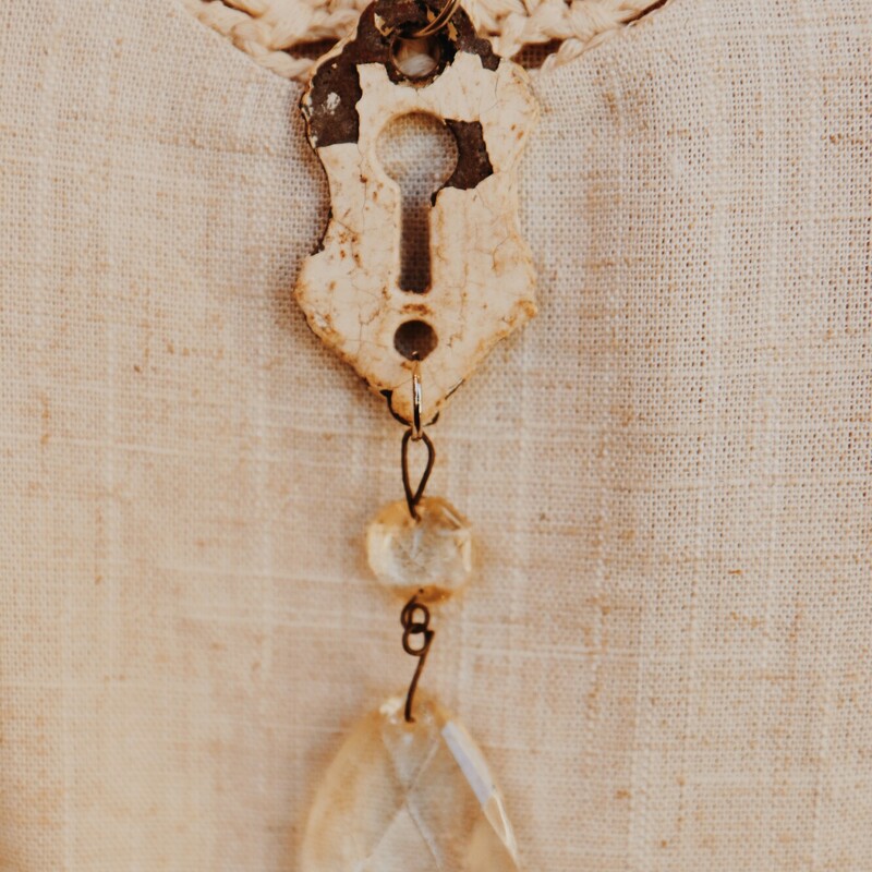 This hand crafted necklace has an antique key hole as its pendant with a crystal hanging from it. It is on a 25 inch chain.