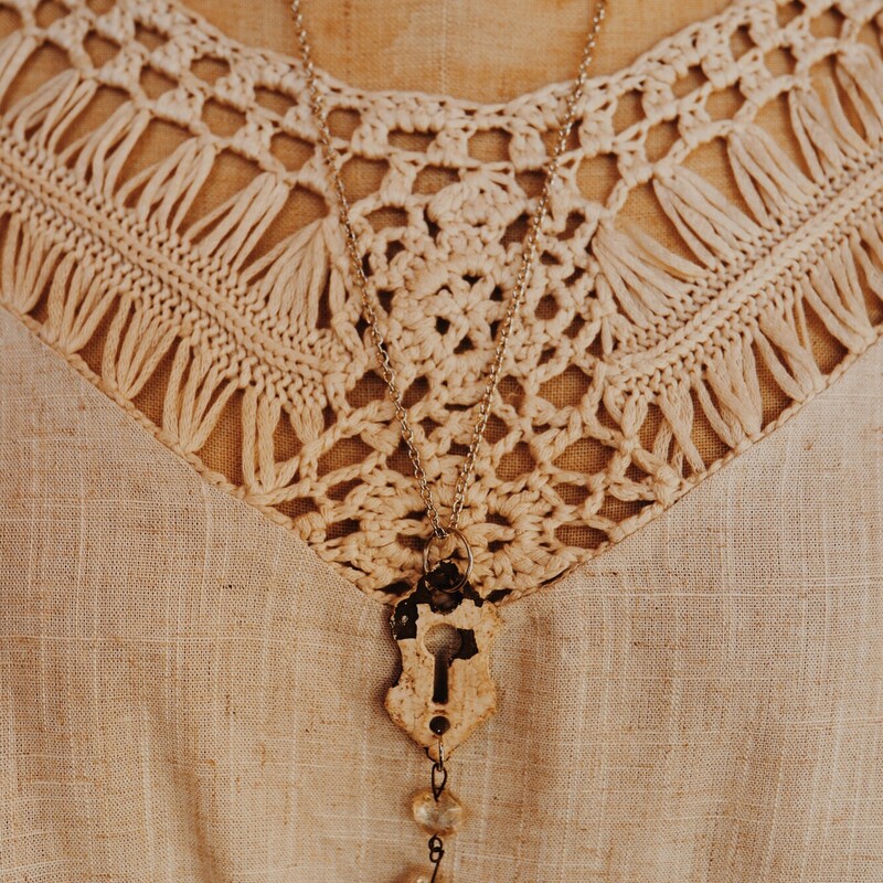 This hand crafted necklace has an antique key hole as its pendant with a crystal hanging from it. It is on a 25 inch chain.