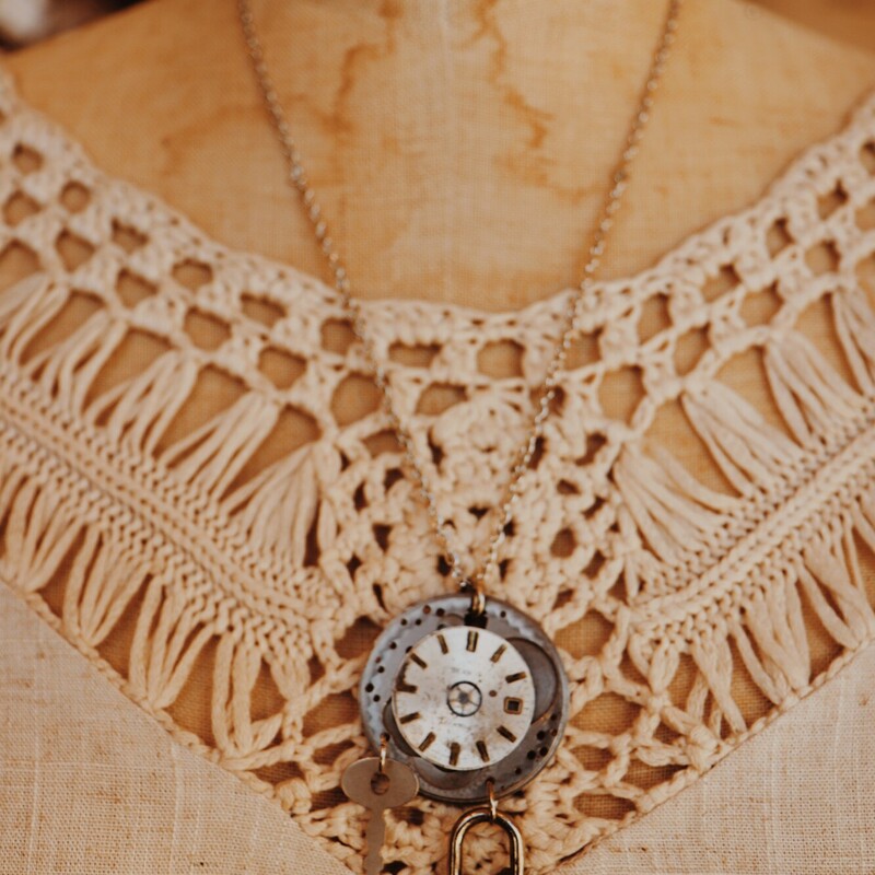 This unique necklace has an antique clock face on the pendant, and a key and padlock hang from it. This beauty hangs on a 21 inch chain