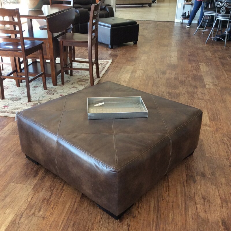Officially, it's called the Gold Rush Cafe Cocktail Ottoman. This super-sized ottoman has been upholstered in a dark brown leather with stitching. Priced to move!