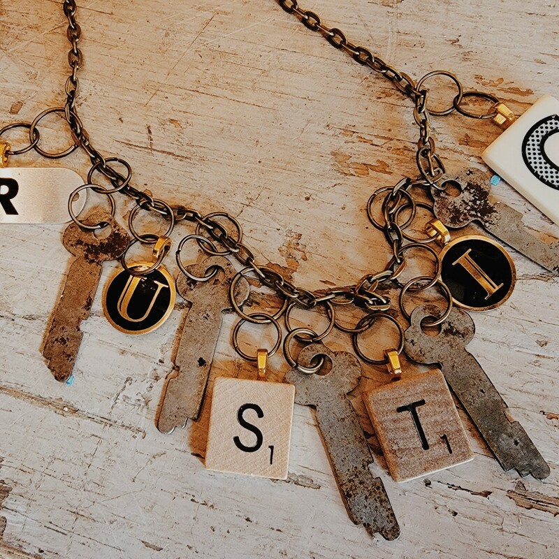 This one of a kind necklace spells out 'rustic' in game pieces and also has hanging keys. This necklace is on a 26 inch chain.