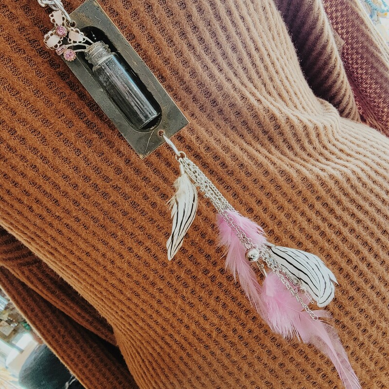 - Hand crafted necklace
- 30 Inch chain
- Escutcheon pendant with bottle inside
- 6 Inches of feathers