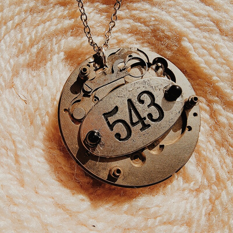 - Hand crafted necklace
- 22 Inch chain
- Clockwork pendant with 543 on the front
