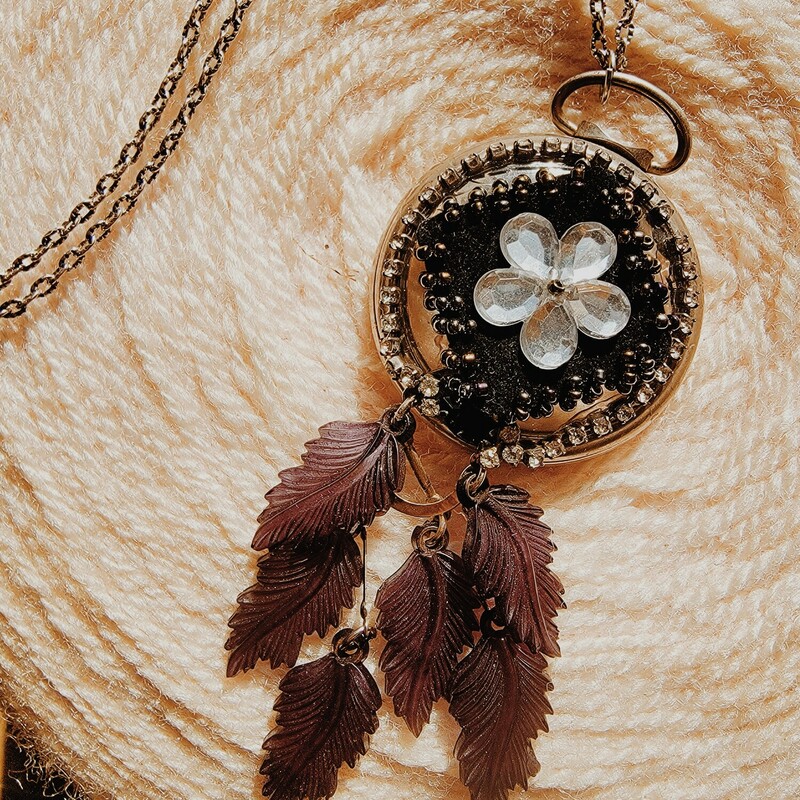 - Hand crafted necklace
- 32 Inch chain
- Pocket watch pendant with flower center
- Black plastic feathers