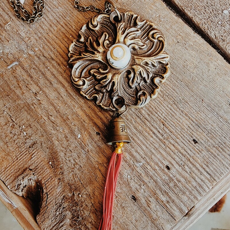 - Hand crafted necklace
- 32 Inch chain
- Red 2 inch tassel
- Brass flower pendant with pearl center
