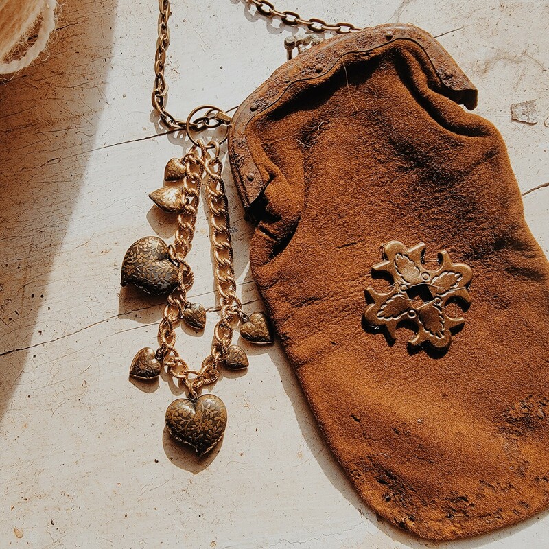 - Hand crafted necklace<br />
- Antique coin purse pendant<br />
- Strand of metal hearts charm<br />
- 32 Inch chain<br />
- 6 Inch coin purse
