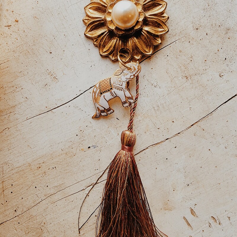 This beautiful necklace was hand crafted! It has a vintage floral medallion as the pendant with a pearl center, and a lovely white, gold, and black elephant hangs from it. The tassel is 4 inches long, and the chain is 34 inches.