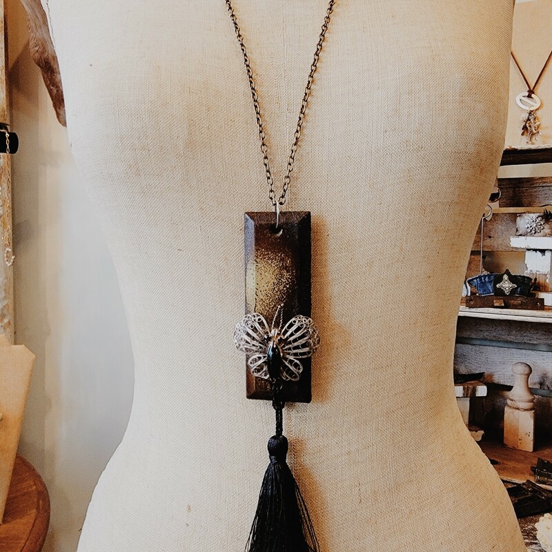 This one of a kind necklace was hand crafted! The artist used an old metal piece for the pendant and attached an antique butterfly charm to the front. A 4 inch black tassel hangs from the pendant.
Chain: 31 Inches