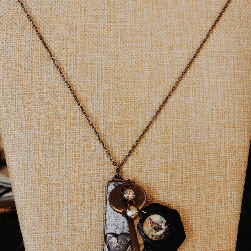 This necklace from Kelli Hawk Designs was handmade from vintage pieces! The centerpiece features two vintage metal pieces, one of which is an old key, as well as a religious picture in a leather circle. This hangs on a 22 inch chain.