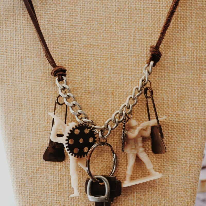 This necklace from Kelli Hawk Designs was handmade! This one of a kind jewelry features a variety of penants hanging along a silver chain that is connected to leather cording.
Charms from left to right:
Old safety pin, army man, clockwork gear, brass key, clockwork gear, army man, old safety pin
Chain: 17 Inches