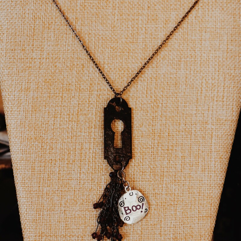 This handmade Kelli Hawk Designs necklace has a keyhole pendant with a purple beaded tassel charm and a charm that reads Boo. This is on a 20 inch chain.