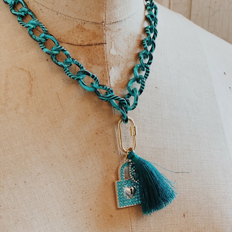 This Kelli Hawk Designs necklace is so fun and makes a statement! It is on a 17 inch turquoise and black chain with a 3 inch extender. A teal tassel and blue rhinestoned lock hang from this chain.