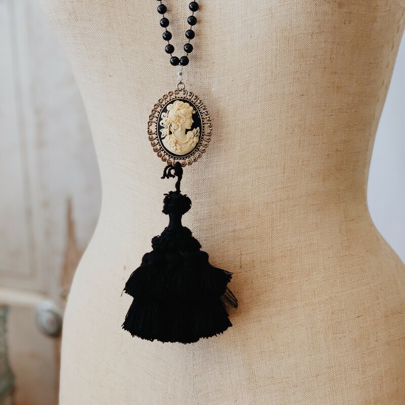 This Kelli Hawk Designs necklace is on a 32 inch strand of beads. The pendant is a beautiful black and cream cameo with a large black tassel attached!