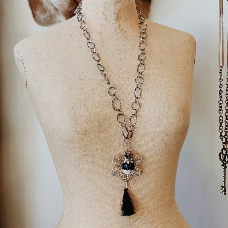 This necklace by Kelli Hawk Designs is truly one of a kind! It is on an excentric 30 inch chain with a 3 inch extender and has a silver flower pendant with a porcelain doll face attached and a black tassel hanging from it.